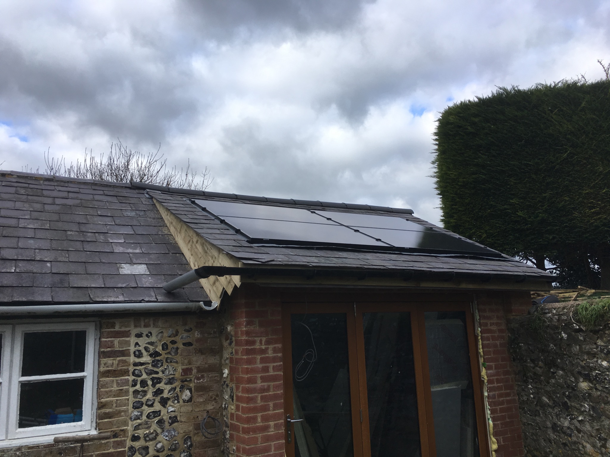 Solar panels installed on a flint cottage roof in West Sussex