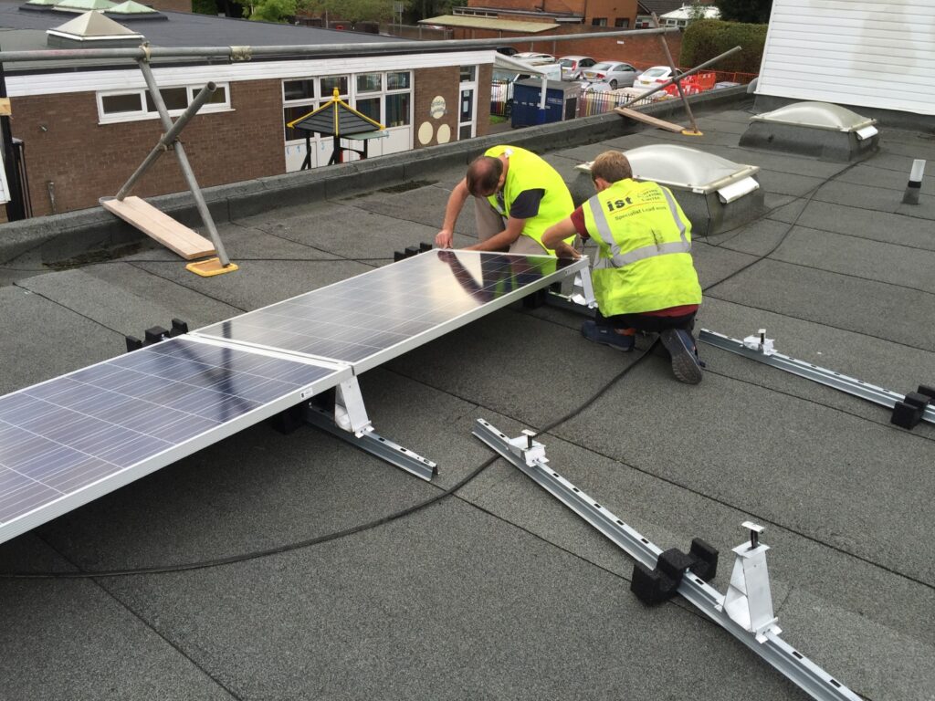 Two Brightspark employees installing PV panels on roof